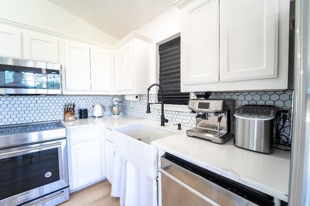 9471 Twin Creeks Cir, Anna, TX 75409 - kitchen with appliances with stainless steel finishes, white cabinets, vaulted ceiling, tasteful backsplash, and light stone countertops
