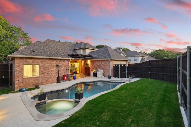 back of property at dusk featuring brick siding, a pool with connected hot tub, a patio area, and roof with shingles