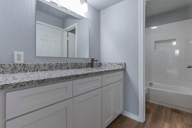 8721 N Normandale St, Fort Worth, TX 76116 - full bath featuring wood finished floors, vanity, bathing tub / shower combination, baseboards, and a textured wall
