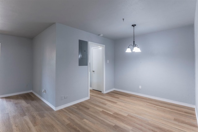 8721 N Normandale St, Fort Worth, TX 76116 - empty room with electric panel, light wood-style floors, baseboards, a chandelier, and fire sprinkler in ceiling