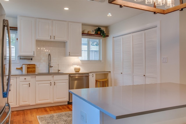 1205 Ranier St, Dallas, TX 75208 - kitchen featuring a sink, light wood-type flooring, stainless steel dishwasher, backsplash, and recessed lighting