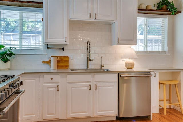 1205 Ranier St, Dallas, TX 75208 - kitchen featuring appliances with stainless steel finishes, a sink, white cabinetry, and backsplash
