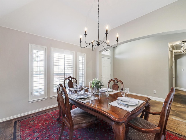 dining space with wood finished floors, baseboards, a chandelier, and lofted ceiling