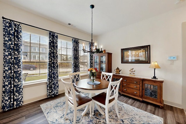 dining room with a chandelier, wood finished floors, and baseboards