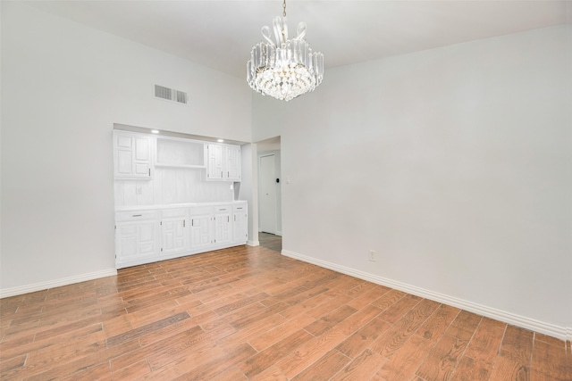 3243 Weather Vane Ln, Dallas, TX 75228 - empty room with a chandelier, baseboards, light wood-style flooring, and a high ceiling
