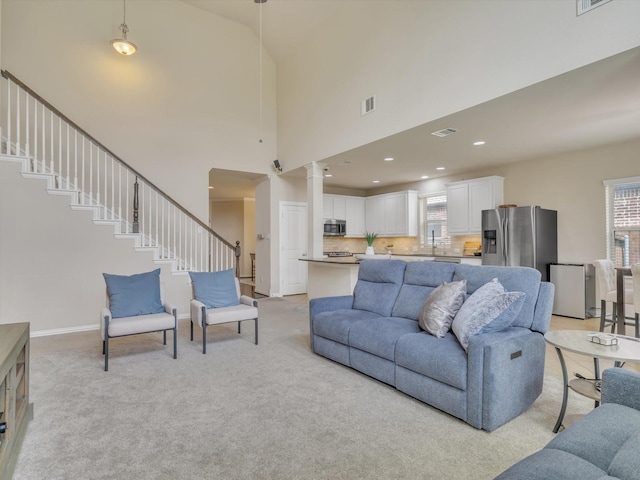 8400 Whistling Duck, Fort Worth, TX 76118 - living room featuring light carpet, stairs, a high ceiling, baseboards, and decorative columns