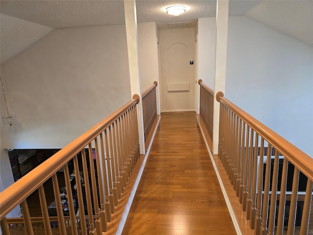 1910 Roselle Ct, Arlington, TX 76018 - hallway with vaulted ceiling, wood finished floors, a wainscoted wall, and a textured ceiling