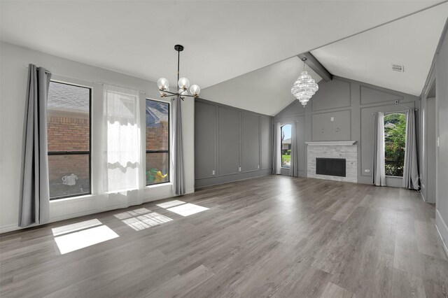 2718 Laurel Oaks Dr, Garland, TX 75044 - unfurnished living room with a chandelier, a stone fireplace, light wood-type flooring, and a decorative wall