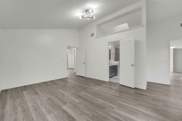 2718 Laurel Oaks Dr, Garland, TX 75044 - unfurnished living room with a textured ceiling, wood finished floors, baseboards, and high vaulted ceiling