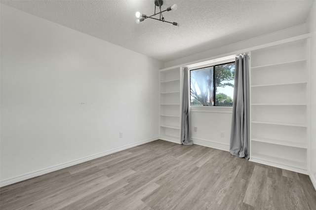 2718 Laurel Oaks Dr, Garland, TX 75044 - empty room with a textured ceiling, a chandelier, wood finished floors, built in shelves, and baseboards