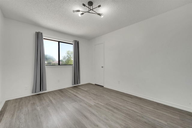 2718 Laurel Oaks Dr, Garland, TX 75044 - empty room featuring a textured ceiling, wood finished floors, a chandelier, and baseboards