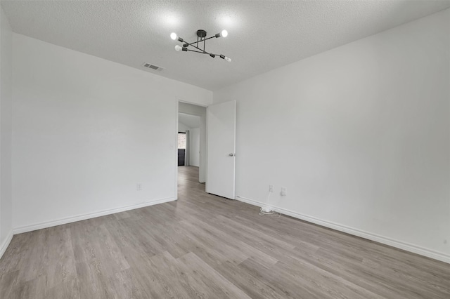 2718 Laurel Oaks Dr, Garland, TX 75044 - spare room with wood finished floors, a chandelier, a textured ceiling, and baseboards