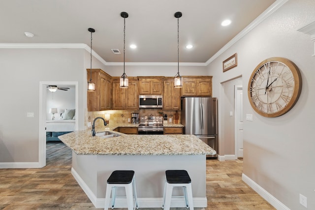 2607 Austin Dr, Granbury, TX 76048 - kitchen featuring stainless steel appliances, a sink, light wood-style floors, backsplash, and light stone countertops