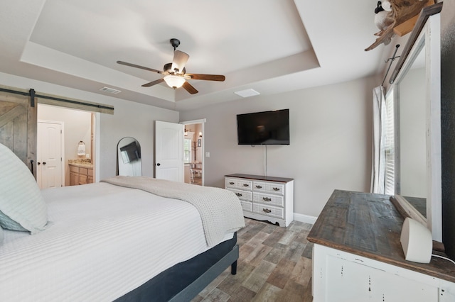 2607 Austin Dr, Granbury, TX 76048 - bedroom with a raised ceiling, a barn door, wood finished floors, baseboards, and ensuite bath
