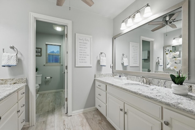 full bathroom featuring a ceiling fan, toilet, wood finished floors, vanity, and baseboards