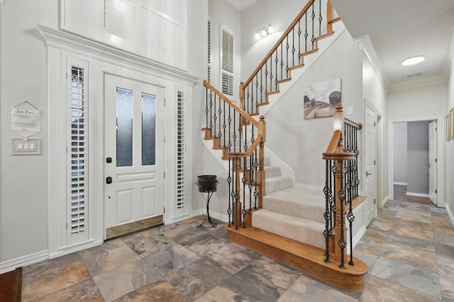 foyer entrance with stone finish floors, stairway, baseboards, and ornamental molding