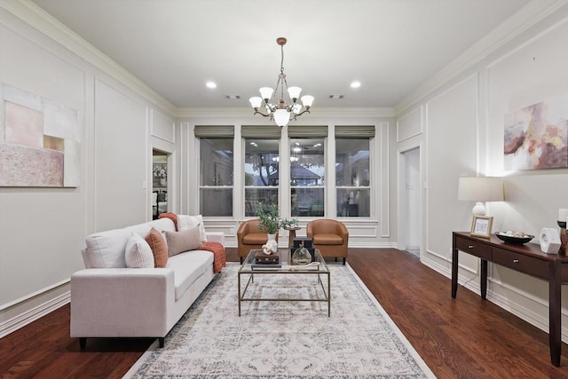 living area featuring a chandelier, a decorative wall, dark wood finished floors, ornamental molding, and recessed lighting