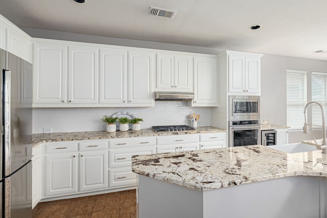 7112 Royal Glen Trl, Mckinney, TX 75072 - kitchen with stainless steel appliances, a sink, under cabinet range hood, and light stone counters