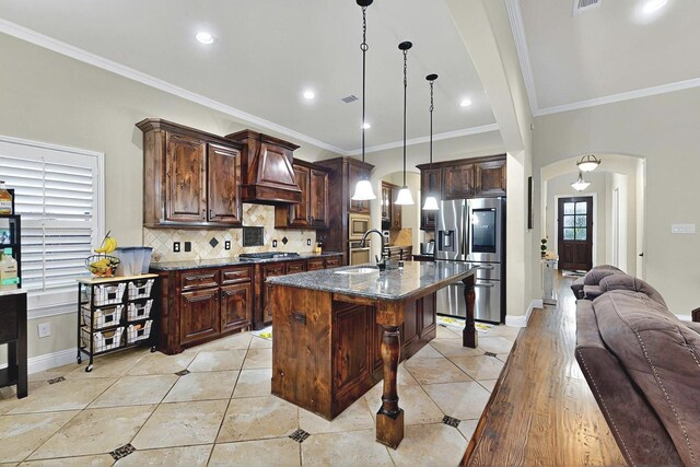 4018 Bear Creek Ct, Celina, TX 75078 - kitchen featuring appliances with stainless steel finishes, arched walkways, a sink, open floor plan, and premium range hood