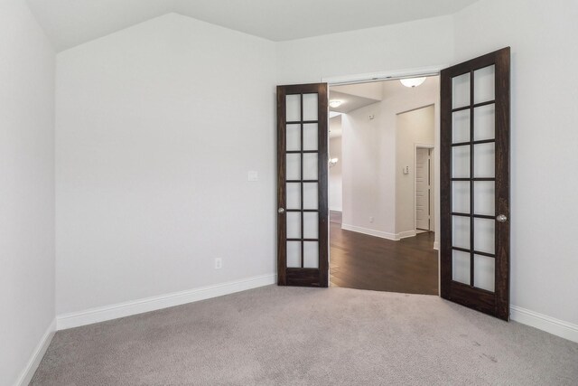 carpeted empty room with french doors, baseboards, and lofted ceiling