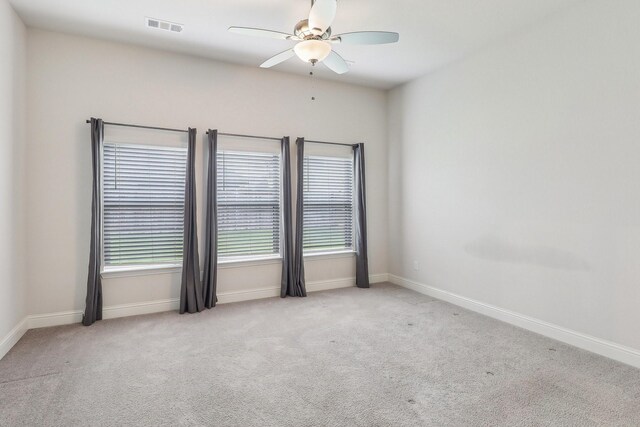 carpeted spare room featuring a ceiling fan and baseboards