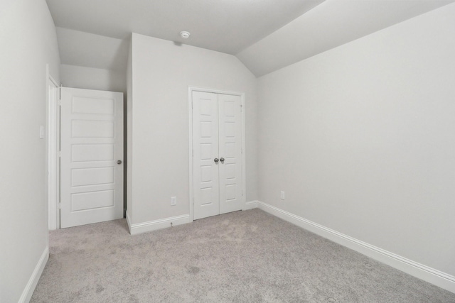 unfurnished bedroom with carpet floors, lofted ceiling, baseboards, and a closet