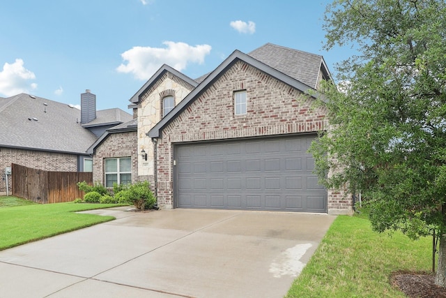 french country style house with concrete driveway, roof with shingles, an attached garage, brick siding, and a chimney