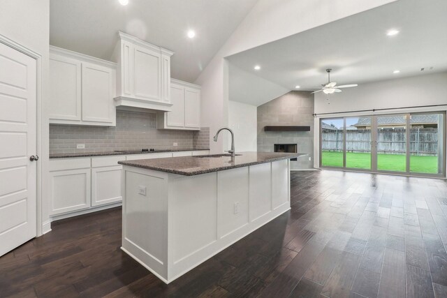 kitchen with a sink, lofted ceiling, ceiling fan, a large fireplace, and open floor plan
