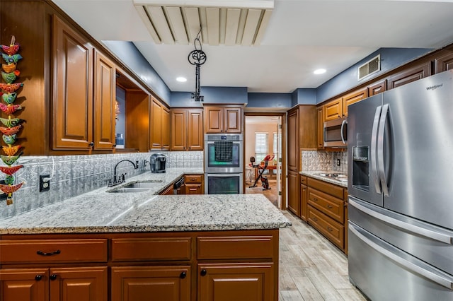 2715 Peach Tree Dr, Carrollton, TX 75006 - kitchen with stainless steel appliances, a sink, light stone countertops, light wood-type flooring, and tasteful backsplash