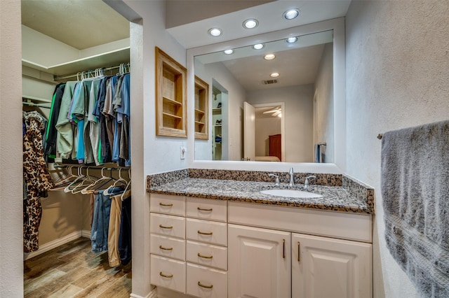 2715 Peach Tree Dr, Carrollton, TX 75006 - bathroom with wood finished floors, recessed lighting, a spacious closet, vanity, and baseboards