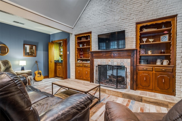 2715 Peach Tree Dr, Carrollton, TX 75006 - living room with vaulted ceiling, a tile fireplace, crown molding, and light wood-style floors
