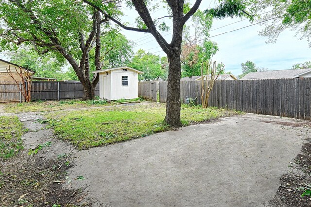fenced backyard featuring a shed, an outbuilding, and a patio area