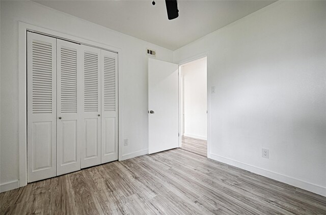unfurnished bedroom featuring a closet, wood finished floors, baseboards, and ceiling fan