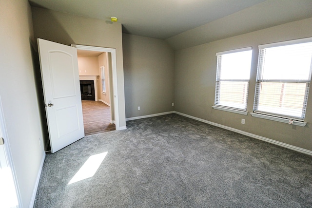 504 Lakeway Ln, Justin, TX 76247 - unfurnished bedroom with dark colored carpet, baseboards, lofted ceiling, and a fireplace
