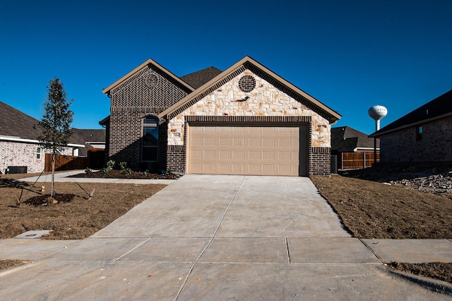 504 Lakeway Ln, Justin, TX 76247 - french provincial home with driveway, a garage, fence, central AC unit, and stone siding