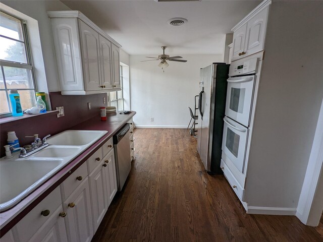kitchen with stainless steel appliances, dark wood-type flooring, white cabinetry, a ceiling fan, and baseboards