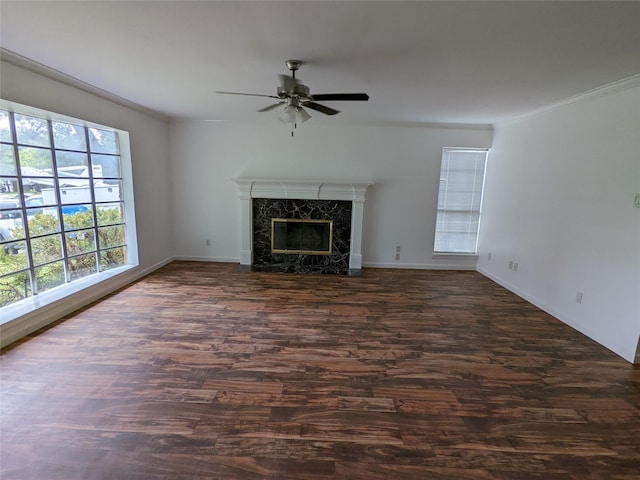 unfurnished living room featuring a ceiling fan, dark wood-type flooring, crown molding, a premium fireplace, and baseboards