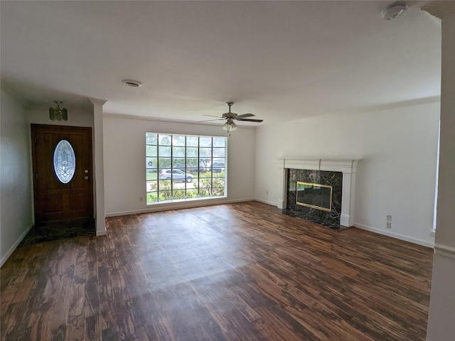 unfurnished living room with dark wood-style flooring, a ceiling fan, a premium fireplace, and baseboards
