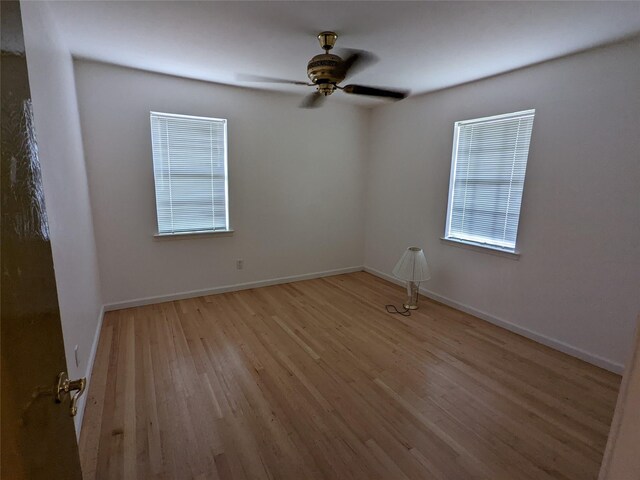 unfurnished room with light wood-type flooring, a ceiling fan, baseboards, and healthy amount of natural light