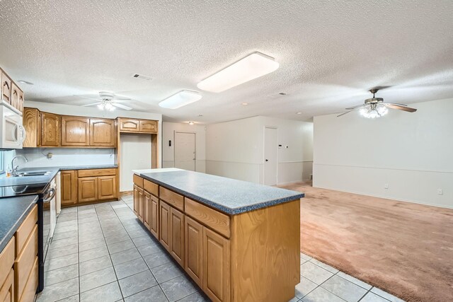107 San Medina Ln, Joshua, TX 76058 - kitchen with black electric range, ceiling fan, white microwave, a sink, and light tile patterned flooring