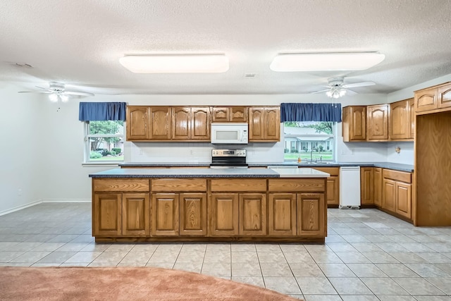 107 San Medina Ln, Joshua, TX 76058 - kitchen featuring white microwave, stainless steel electric range, a sink, a ceiling fan, and a textured ceiling