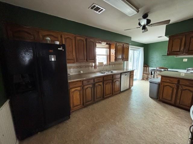 2220 N Clements St, Gainesville, TX 76240 - kitchen with black fridge, stainless steel dishwasher, a sink, a ceiling fan, and light countertops