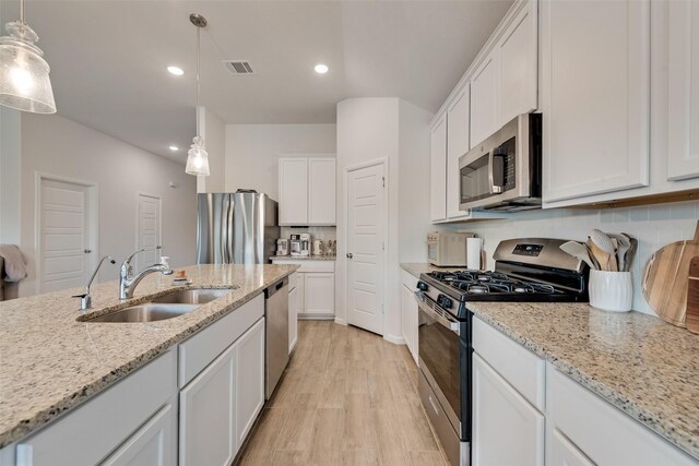 148 Greenback Trl, Fort Worth, TX 76131 - kitchen with stainless steel appliances, a sink, light wood-style flooring, white cabinetry, and decorative backsplash