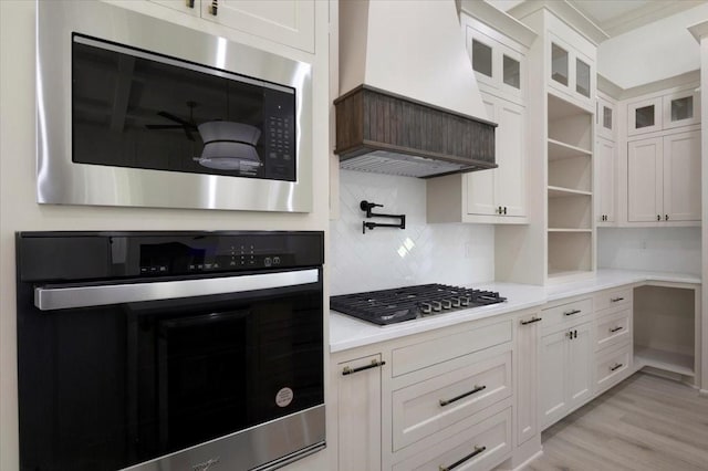14541 Woodland Crk, Tyler, TX 75706 - kitchen with appliances with stainless steel finishes, custom range hood, white cabinetry, light countertops, and decorative backsplash