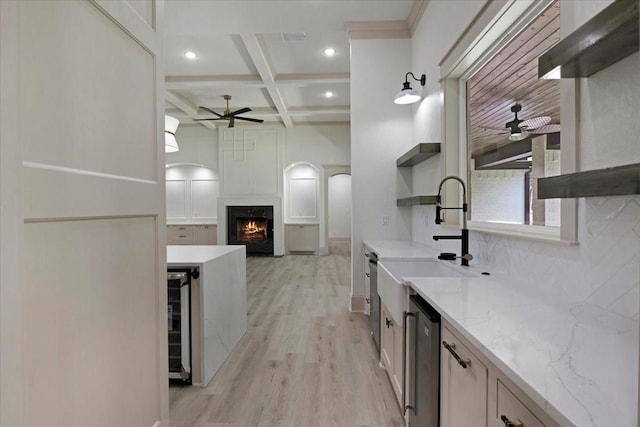 14541 Woodland Crk, Tyler, TX 75706 - kitchen with ceiling fan, open shelves, a warm lit fireplace, light wood-type flooring, and beam ceiling