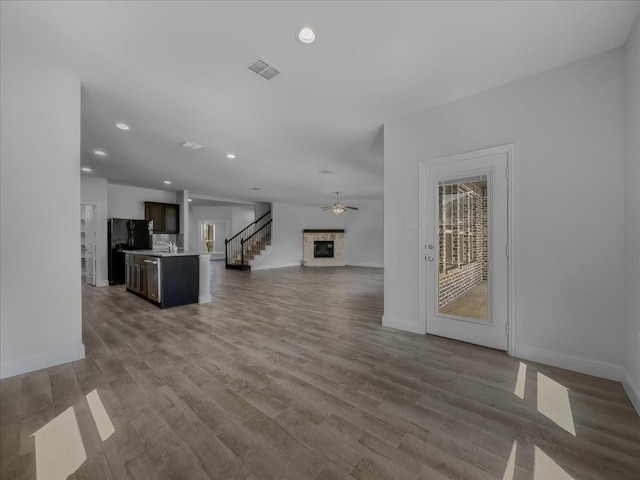 unfurnished living room with baseboards, stairway, a fireplace, and recessed lighting