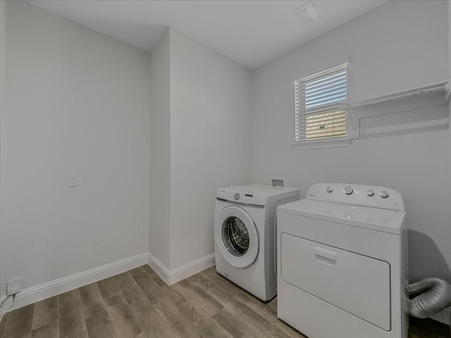 laundry room featuring washing machine and clothes dryer, light wood-type flooring, and baseboards
