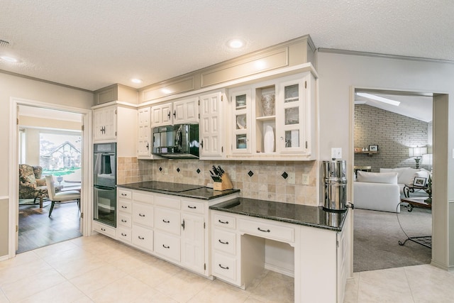 kitchen with black appliances, a textured ceiling, light tile patterned floors, tasteful backsplash, and glass insert cabinets