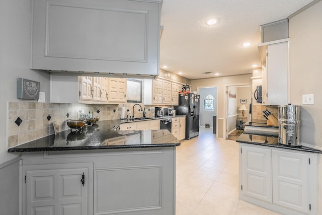 2314 Wakeforest Ct, Arlington, TX 76012 - kitchen with black appliances, a sink, decorative backsplash, dark stone counters, and a peninsula