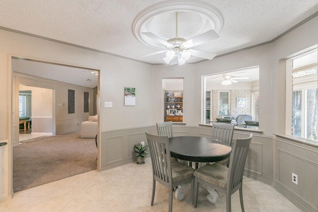 dining room with a decorative wall, ceiling fan, a textured ceiling, light tile patterned floors, and light colored carpet